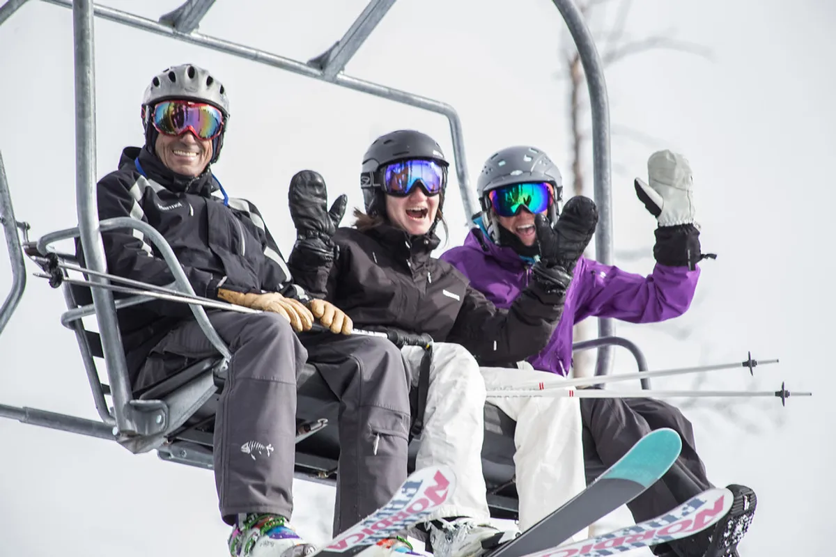 A lively exterior winter scene featuring a ski lift in operation, skiers and snowboarders gliding down snowy runs, and groups socializing near the lodge. The landscape is blanketed in fresh snow, exuding the thrill and accessibility of winter mountain adventures.